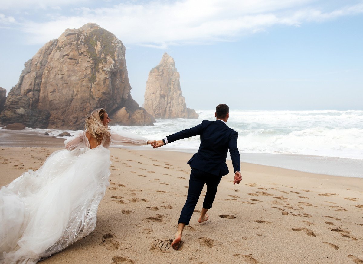 happy newlyweds holding their hands are running across beach atlantic ocean11